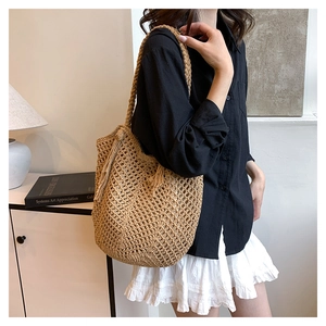 Close-up of woven hollow mesh tote bag with tassel detail and natural wood finish