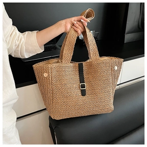 Détail du sac cabas en paille tressée avec sangle en cuir noir et boucle dorée