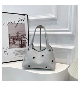 Detail of silver-grey lychee leather shoulder bag with large metal rivet eyelets decor