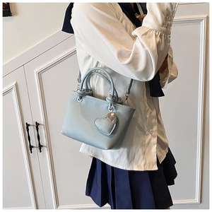 Light blue lychee leather bucket bag with heart charm shown on model in side view