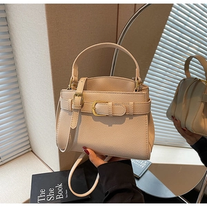 Gros plan détaillé du sac à main en cuir grainé crème avec boucle dorée et bandoulière