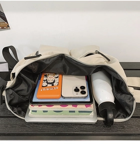 Large capacity messenger bag interior showing a laptop, tablet, books, and water bottle