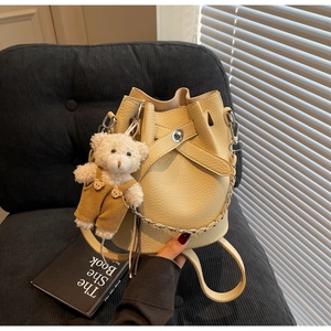 Detail of cream bucket bag showing lychee grain texture and cute plush bear charm