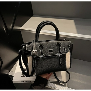 Close-up of black leather and beige canvas Kelly bag with contrast stitching and metal buckle