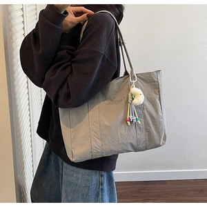 Close-up of a grey casual tote bag with moon pendant and embroidery detail