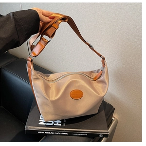 Detail of apricot oxford nylon crescent bag featuring brown strap and fashion leather tag