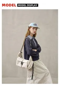 Outdoor shot of a large beige canvas messenger bag with pockets on a stylish model