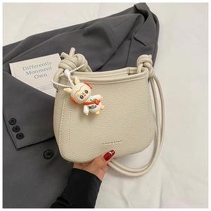 Detail of off-white lychee texture bag with fashion text and cute astronaut bunny charm