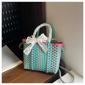 Detail of colorful woven basket bag with white lace bow and mint green shoulder strap