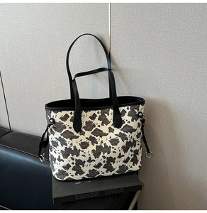 Vista dettagliata di una grande borsa tote con stampa mucca e coulisse laterali