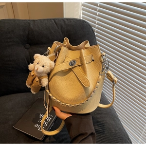 Detail of yellow bucket bag with lychee pattern leather and plush bear charm