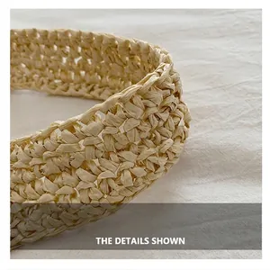 Macro detail of the hand-woven beige straw handle on a stylish bucket beach bag
