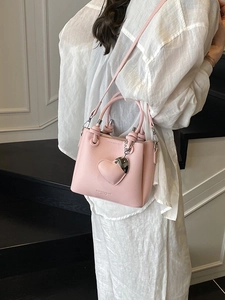 Pink lychee grain bucket bag with heart pendant shown in a modern interior setting