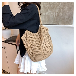 Detail of hand-woven straw tote bag featuring long decorative tassels and natural texture