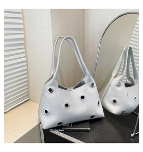 Detail of silver textured leather shoulder bag with metallic eyelets and rivets decoration