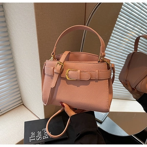 Détail d'un sac à main en cuir rose grainé avec boucles dorées et bandoulière réglable