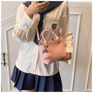 Detail of light pink bucket bag with lychee texture and heart charm in a studio setting