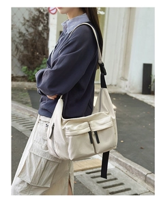 Detail of off-white nylon crossbody bag with large front flap pockets and adjustable strap