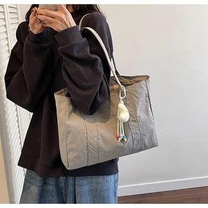 Gray large tote bag with textured fabric, white strap and cute doll pendant detail