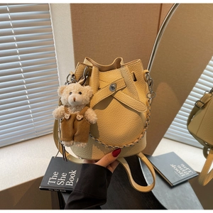 Detail of beige bucket bag with pebble leather texture and cute teddy bear charm