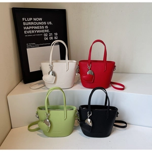Mini bucket bags in red, green, black and white with heart charms on display steps