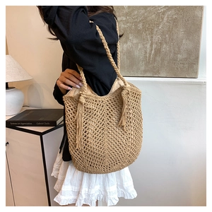Detail of hand-woven hollow tote bag featuring decorative tassels and braided straps