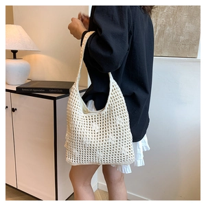 Close-up of beige hollow knit tote bag showing intricate crochet mesh and strap detail