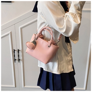 Pink lychee grain bucket bag featuring a cute heart pendant and knotted dual handles