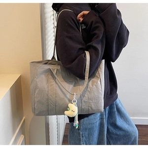Side view of large gray tote bag with long straps and yellow plush moon charm detail