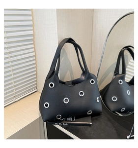 Detail of black pebbled leather underarm bag with silver grommets and dual handles
