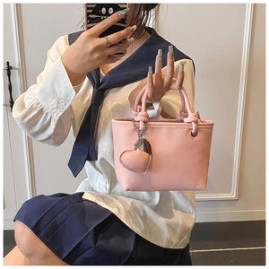 Detail of pink lychee texture leather bucket bag with a cute heart pendant charm