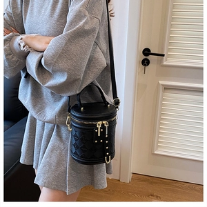 Side view of black quilted bucket bag with gold hardware and adjustable strap on model