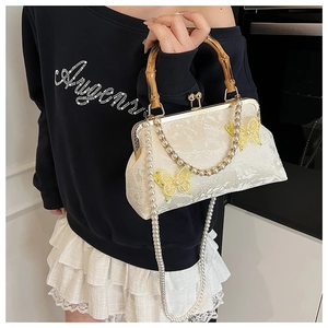 Close-up of vintage lace shell bag with butterfly decor and bamboo handle on model