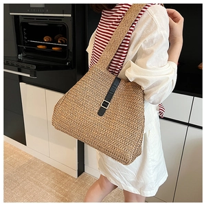 Détail d'un sac cabas tissé avec garniture en cuir noir et boucle dorée élégante