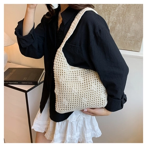 Detail of a cream crochet bucket bag showing the hollow-out woven texture on a shoulder