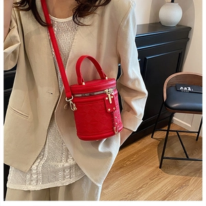 Close-up of a red cylindrical bucket bag with geometric embossed leather and gold hardware
