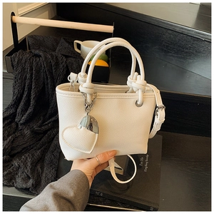 Detailed view of the white litchi pattern bucket bag with a knotted handle and heart charm