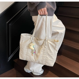 Detailed texture of off-white casual tote bag with moon plush charm and brand logo