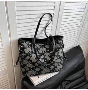 Dettaglio del tessuto jacquard a macchie e del cinturino in pelle nera di una borsa tote