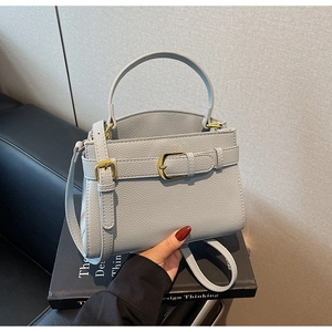 Détail du sac en cuir bleu clair à motif litchi avec boucle dorée et poignée