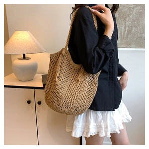 Close-up of beige woven tote bag with fringe tassels and intricate hollow knit details