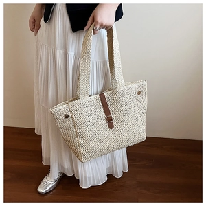 Détail d'un sac cabas en paille tressée avec sangle en cuir marron et boucle