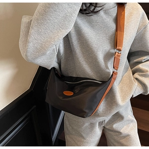 Detail of black crescent oxford bag with brown wide strap and leather patch on side