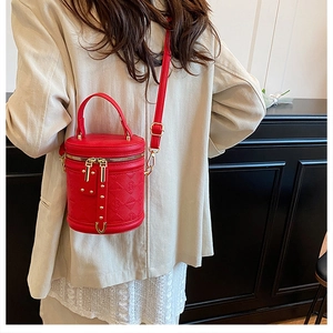 Detail view of red quilted bucket bag with gold hardware and adjustable strap on a model