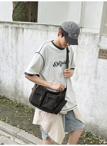 Detail of black nylon crossbody bag featuring utility pockets and durable shoulder strap