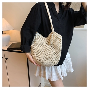 Detail of cream woven crochet tote bag with mesh design and fringe tassel decoration