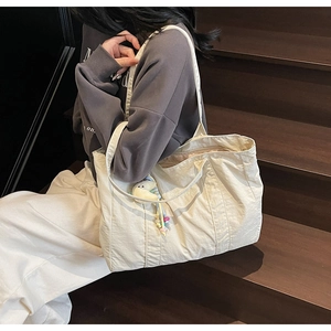 Spacious beige tote bag with embroidery and cute elephant charm on a wooden staircase