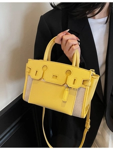 Chic yellow leather and canvas patchwork Kelly style handbag worn by a model in black suit