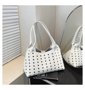 Detail of white lychee leather tote bag with metal eyelet decor and minimalist dual straps