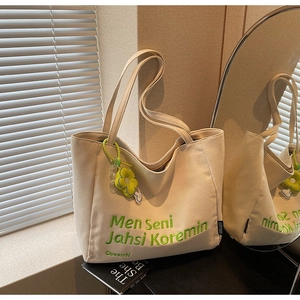 Detail of canvas tote bag featuring green embroidery text and yellow daisy charm